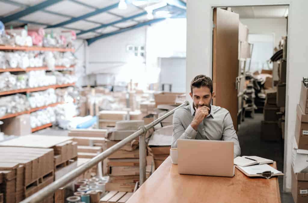 Guy with a laptop in the warehouse viewing inventory